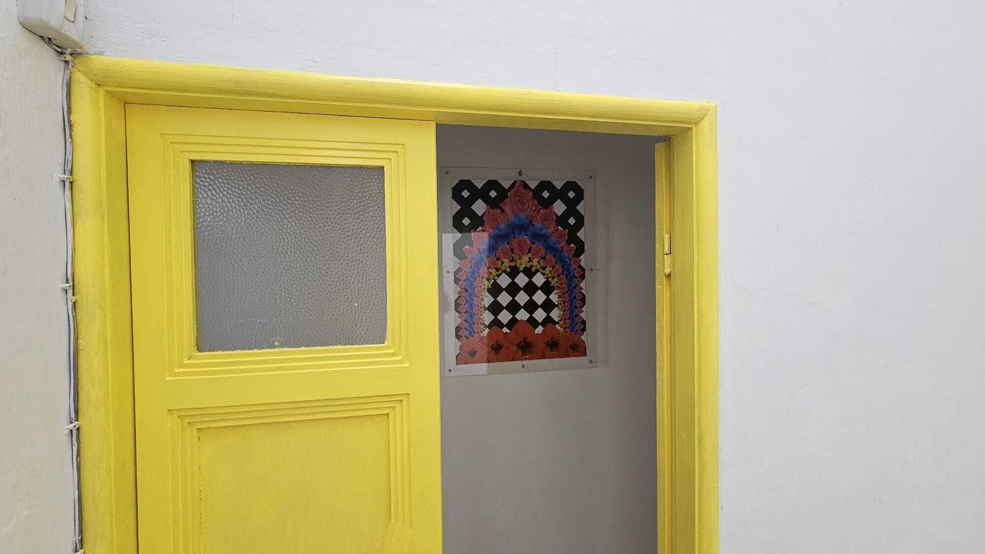A yellow door with a window, a white wall, and a decorative window design.