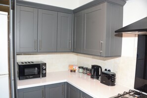 A kitchen with grey cabinets, a microwave, a toaster, and a coffee maker. - Palmers Green | 3BDR | Entire House | Relocation (London)