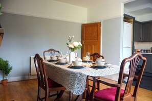 A dining area with a round table set for four, surrounded by wooden chairs. - Palmers Green | 3BDR | Entire House | Relocation (London)