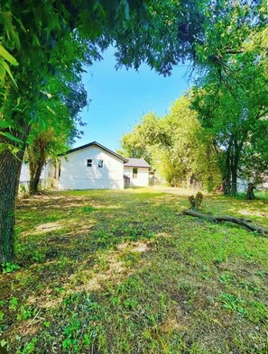 A white building with a flat roof, surrounded by trees and grass.