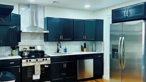 Una cocina moderna con armarios oscuros, electrodomésticos de acero inoxidable y piso de madera.