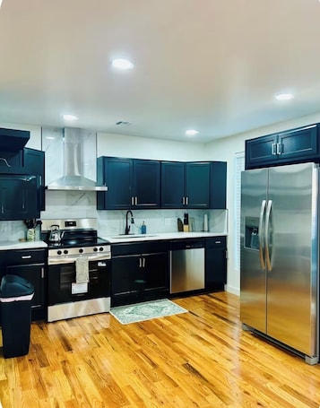 A modern kitchen with dark cabinets, stainless steel appliances, and a wooden floor.. Spacious Modern Glam House Minutes To Downtown