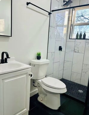 A bathroom with a toilet, sink, and shower area. - Spacious Modern Glam House Minutes To Downtown (Oklahoma City)