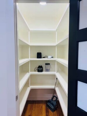 A room with a white shelving unit, a vacuum cleaner, and a power strip on the floor. - Spacious Modern Glam House Minutes To Downtown (Oklahoma City)