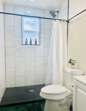 Une salle de bain avec douche, toilettes et une fenêtre donnant sur un beau paysage.