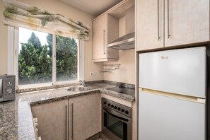 Una cocina con ventana, un fregadero, una estufa y un refrigerador.