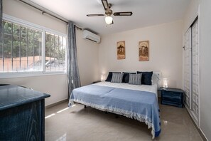 A bedroom with a bed, a desk, a ceiling fan, and a window with curtains. - Casa Burriana – zonnig en gezellig verblijf op 5 min. lopen van het strand. (Nerja)