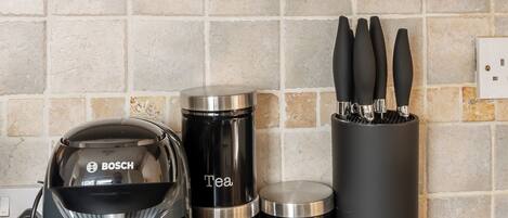 A kitchen with a Bosch coffee maker, a Tassimo pod dispenser, and two stainless steel containers labeled 'Tea' and 'Coffee.'