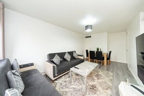 Ein modernes Wohnzimmer mit einer schwarzen Couch, einem Couchtisch und einem Essbereich mit Tisch und Stühlen.