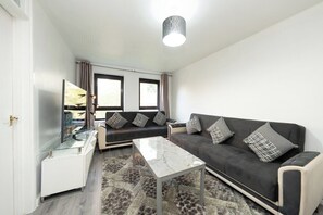 Ein modernes Wohnzimmer mit einer Couch, einem Couchtisch und einem Fernseher.