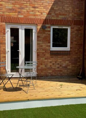 A brick building with a glass door and a window. There is a small table and chairs outside. - Professionals | Entire House | 2BDR | Weekly Deals (London)