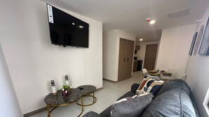 A modern living room with a grey sofa, a small round table, and a flat-screen TV mounted on the wall. - Nuevo Apt Moderno N811/ 4 People (Tegucigalpa)