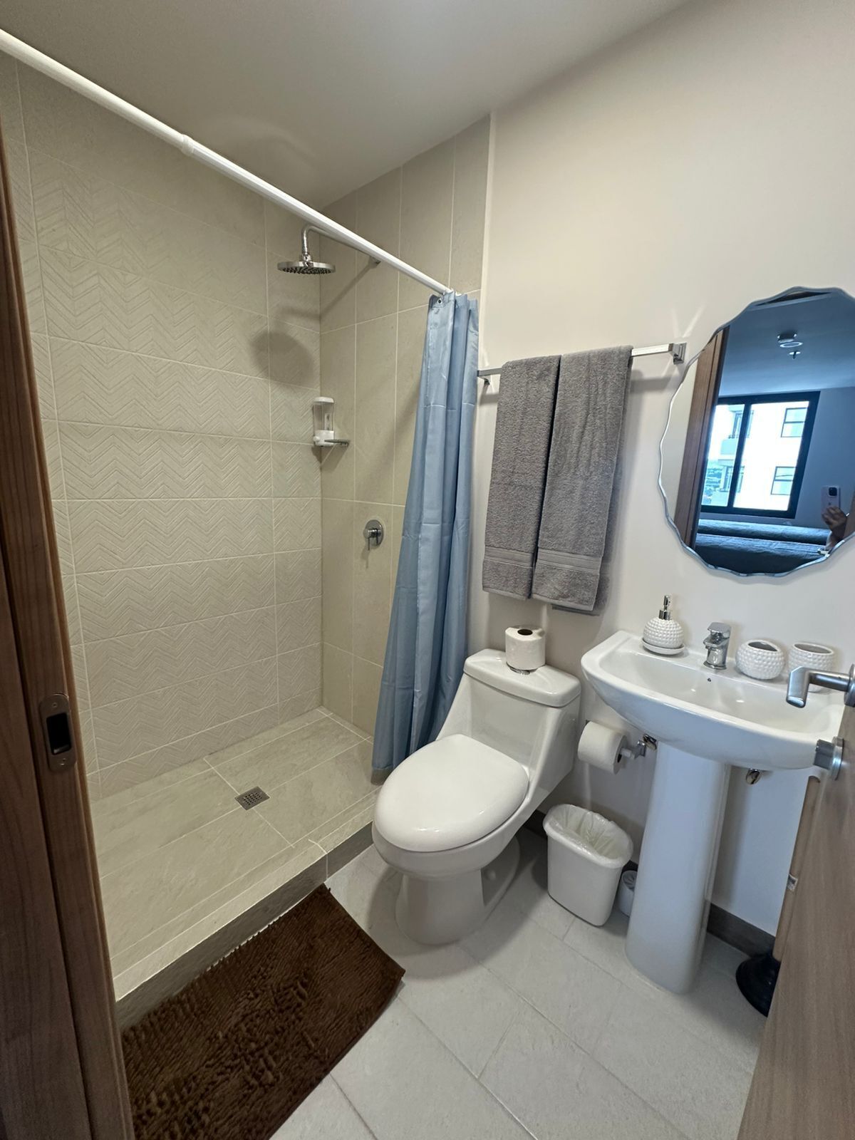 Un bagno con doccia, wc, lavandino e specchio.