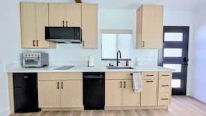 Eine moderne Küche mit Holzausstattung, integriertem Mikrowellenherd, Toaster und Geschirrspüler.
