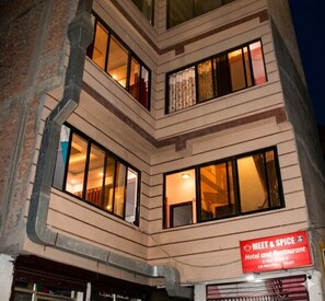 Un hotel con múltiples ventanas, una señalización visible y estructura en esquina.