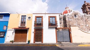 A row of colorful buildings with balconies, a church, and a gate. - Casa San Pedro | Corazón de Cholula, Parking (Puebla)