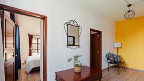 A hotel room with a bed, a wooden dresser, a mirror, a potted plant, a bench, and a lamp. - Casa San Pedro | Corazón de Cholula, Parking (Puebla)
