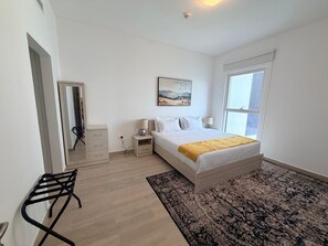 Ein Schlafzimmer mit Bett, Nachttischen, einem Spiegel, einem Fenster und einer Tür.