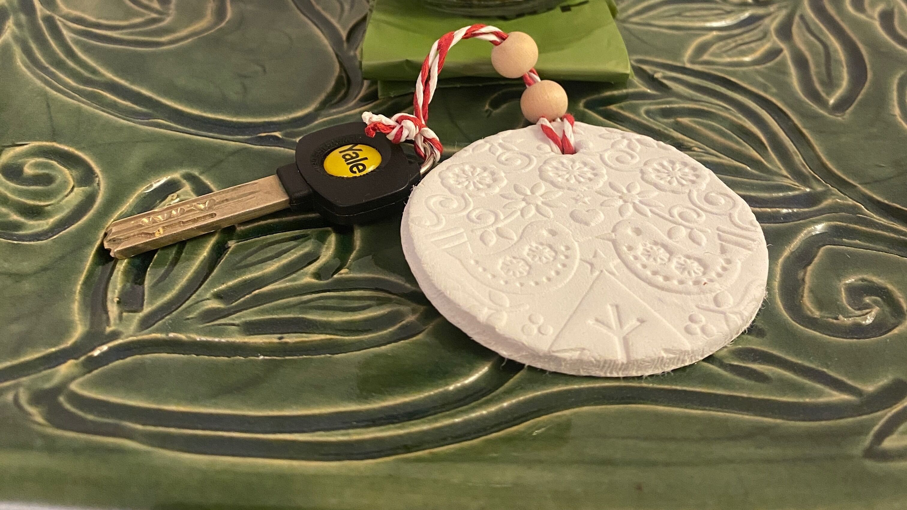 A set of keys with a yellow keychain and a decorative round object with embossed patterns.