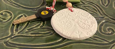 A set of keys with a yellow keychain and a decorative round object with embossed patterns.
