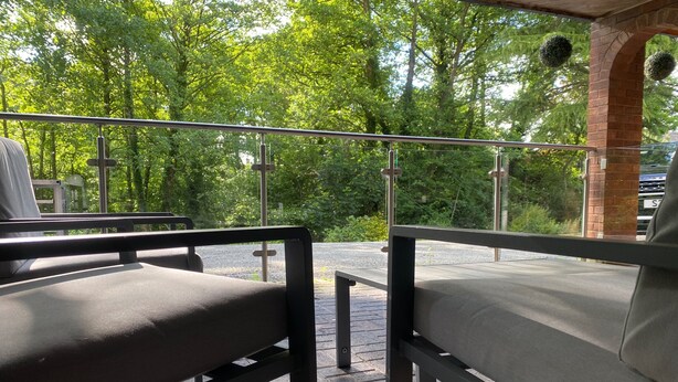An outdoor seating area with two chairs and a table, surrounded by a metal railing, with trees in the background. - Quiet, Modern Ground Floor Annex Near Theatr Clwyd (Mold)
