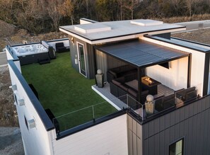 Un espace de vie extérieur moderne comprenant une terrasse, un coin salon et un jacuzzi.