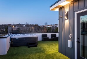 Une terrasse sur le toit avec un jacuzzi, des sièges extérieurs et une vue sur les environs.