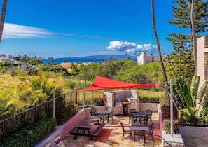 An outdoor patio with a grill, seating, and a view of the ocean. - Surf Rider, Remodeled, Walk Out Lanai, Ocean View, 2ACs, 5 Min Walk to Kam 1 (Kihei)