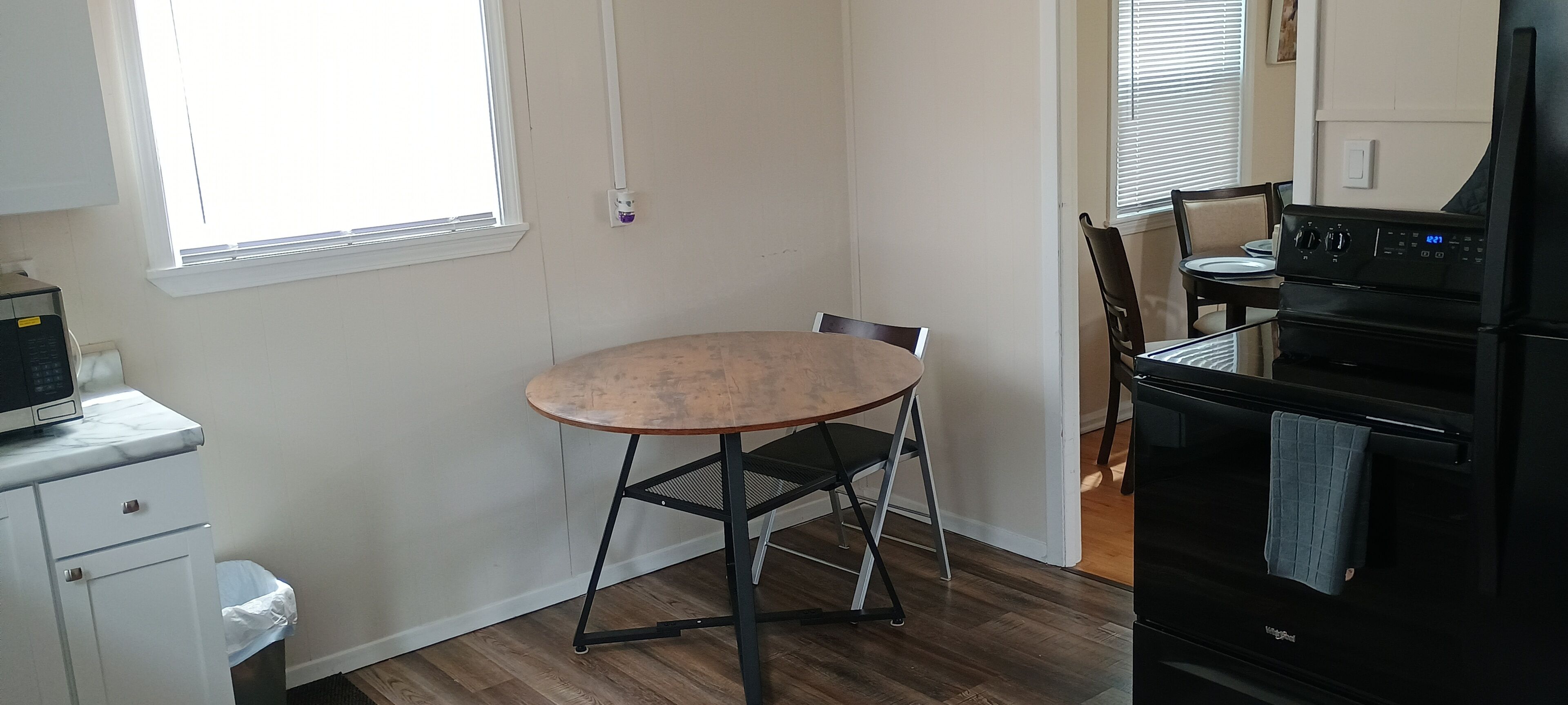 Une cuisine équipée d’une table ronde, d’un four à micro-ondes, d’une cuisinière et d’une poubelle.