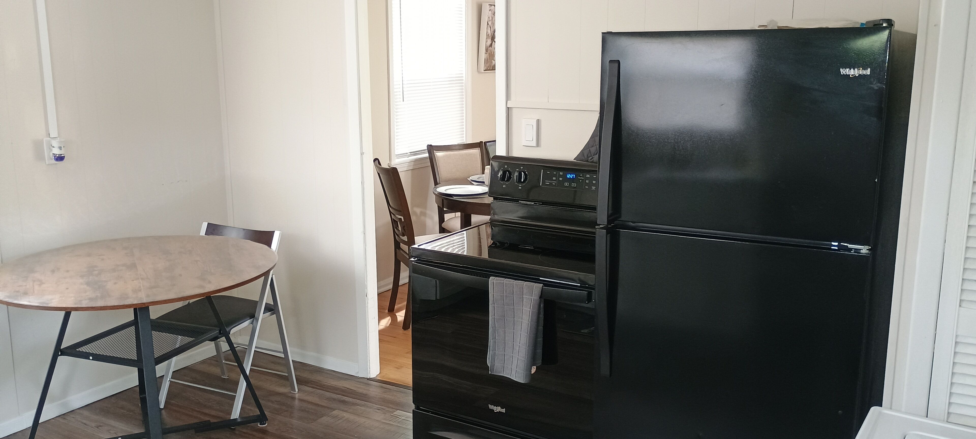 Una cocina compacta con un refrigerador negro, una estufa y una mesa de comedor con sillas.