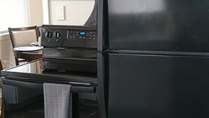 Un réfrigérateur noir doté d’un écran numérique, d’un four intégré et d’une hotte de cuisine en acier inoxydable.