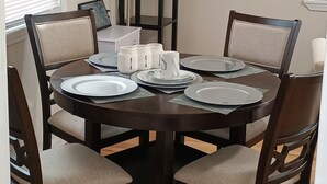 Une salle à manger avec une table ronde, six chaises et un grand lampadaire.