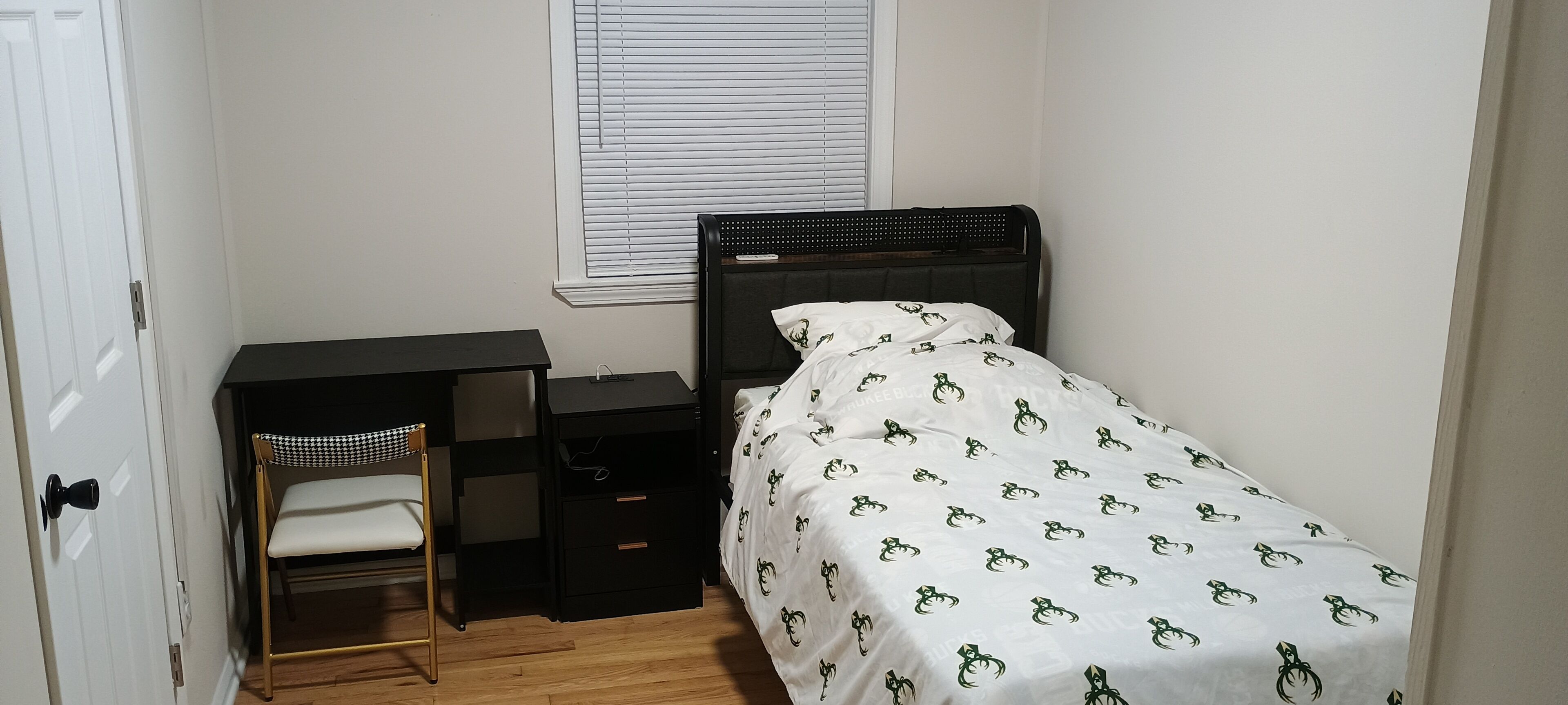 A small bedroom with a single bed, a desk, and a chair.