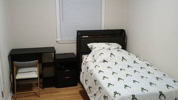 A small bedroom with a single bed, a desk, and a chair.