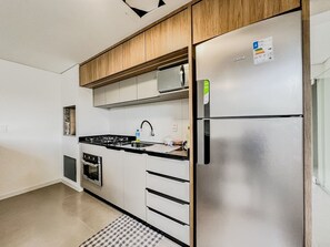 Eine Küche mit einem Edelstahl-Kühlschrank, einem Einbauofen und einer Mikrowelle.