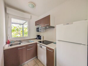 Une cuisine compacte équipée d’une fenêtre, d’un four à micro-ondes, d’une machine à café, d’un lave-vaisselle et d’un réfrigérateur.