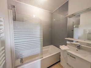 A bathroom with a bathtub, a sink, a mirror, and a shower area. - L'Escale de l'Estuaire, T3 with Pool Near Soulac (Le Verdon-sur-Mer)