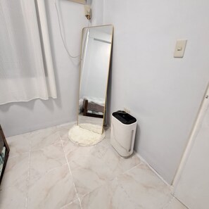 A bathroom with a mirror, a trash bin, and a toilet.