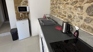 A compact kitchen with a stone wall, a microwave, a sink, and a kettle. - Small 4 person self-catering apartment in LEDENON - Entire apartment (Lédenon)
