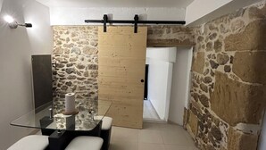 A modern interior with a stone wall, a wooden sliding door, a glass table with chairs, and a light fixture. - Small 4 person self-catering apartment in LEDENON - Entire apartment (Lédenon)