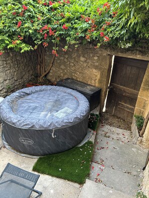 Ein Whirlpool im Spa, eine Steinmauer und eine Holztür.