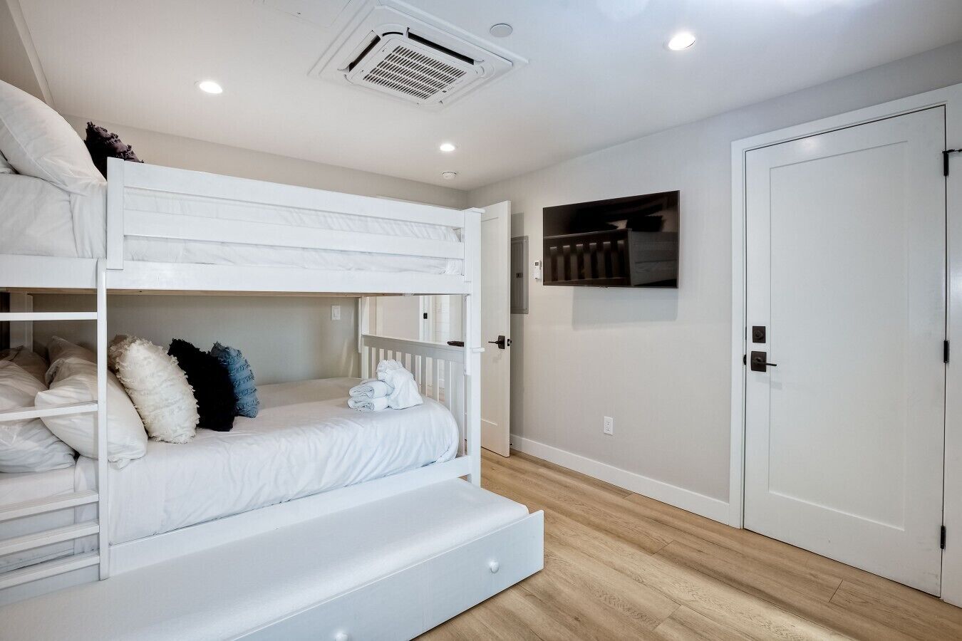 Una camera con un letto a castello, una porta bianca, un piccolo ripiano e un interruttore a muro.