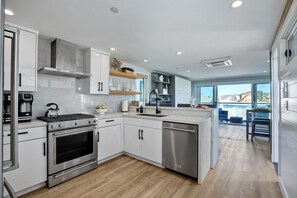 A modern kitchen with white cabinetry, stainless steel appliances, and a wooden floor. - Sleeps 20 Walk to Beach 2 Side-by-Side Homes (San Diego)