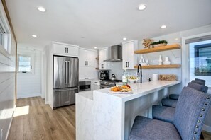 A modern kitchen with white cabinetry, stainless steel appliances, and a marble island. - Sleeps 20 Walk to Beach 2 Side-by-Side Homes (San Diego)