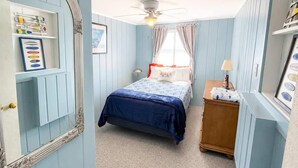 A bedroom with a bed, a nightstand, a mirror, and a ceiling fan. - The only direct-waterfront home at Anchorage — 2BR, 2BA, and lake views from every room. (Iosco County)