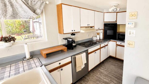 A compact kitchen with a sink, stove, and cabinets. - The only direct-waterfront home at Anchorage — 2BR, 2BA, and lake views from every room. (Iosco County)