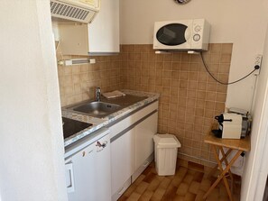 A compact kitchen with a sink, microwave, and a small trash bin. - L’Escapade du Cap, Sea View, Sleeps 6 (Le Cap d'Agde)