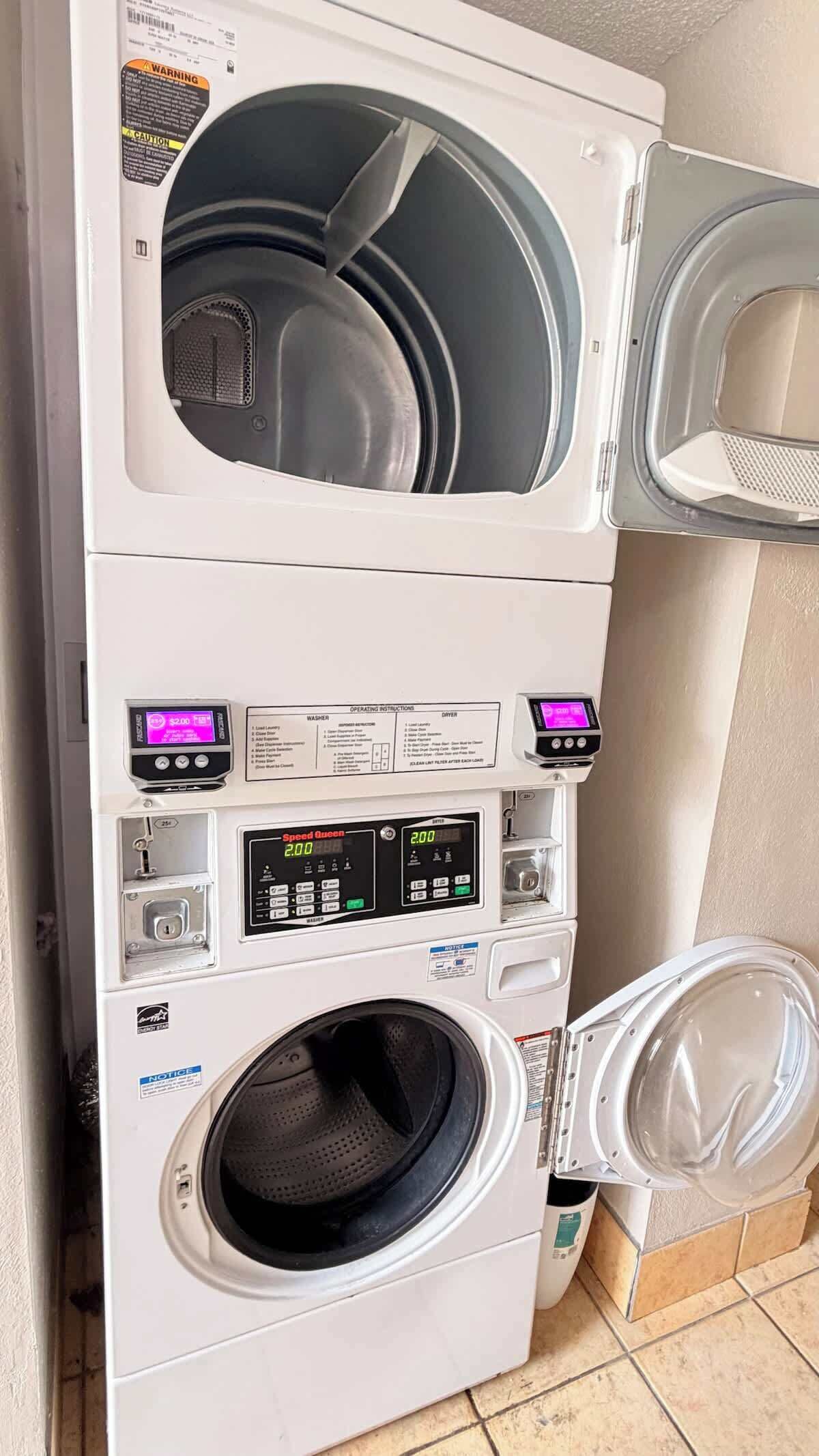 A stacked washer and dryer unit with digital displays, operating instructions, and a price tag.