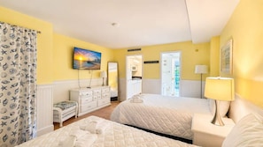 A hotel room with two beds, a TV, a painting, a desk with a lamp, and a bathroom visible through an open door. - Beachside Condo Near Ocean | Pool | Sleeps 6 (Myrtle Beach)