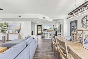 A modern kitchen with a dining area, wooden furniture, and a large clock on the wall. - Themed Luxury Retreat | Pool, BBQ & Arcade (Gilbert)